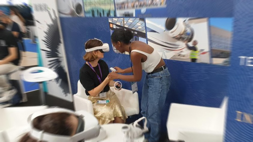 A woman experiencing VR with someone explaining to her.